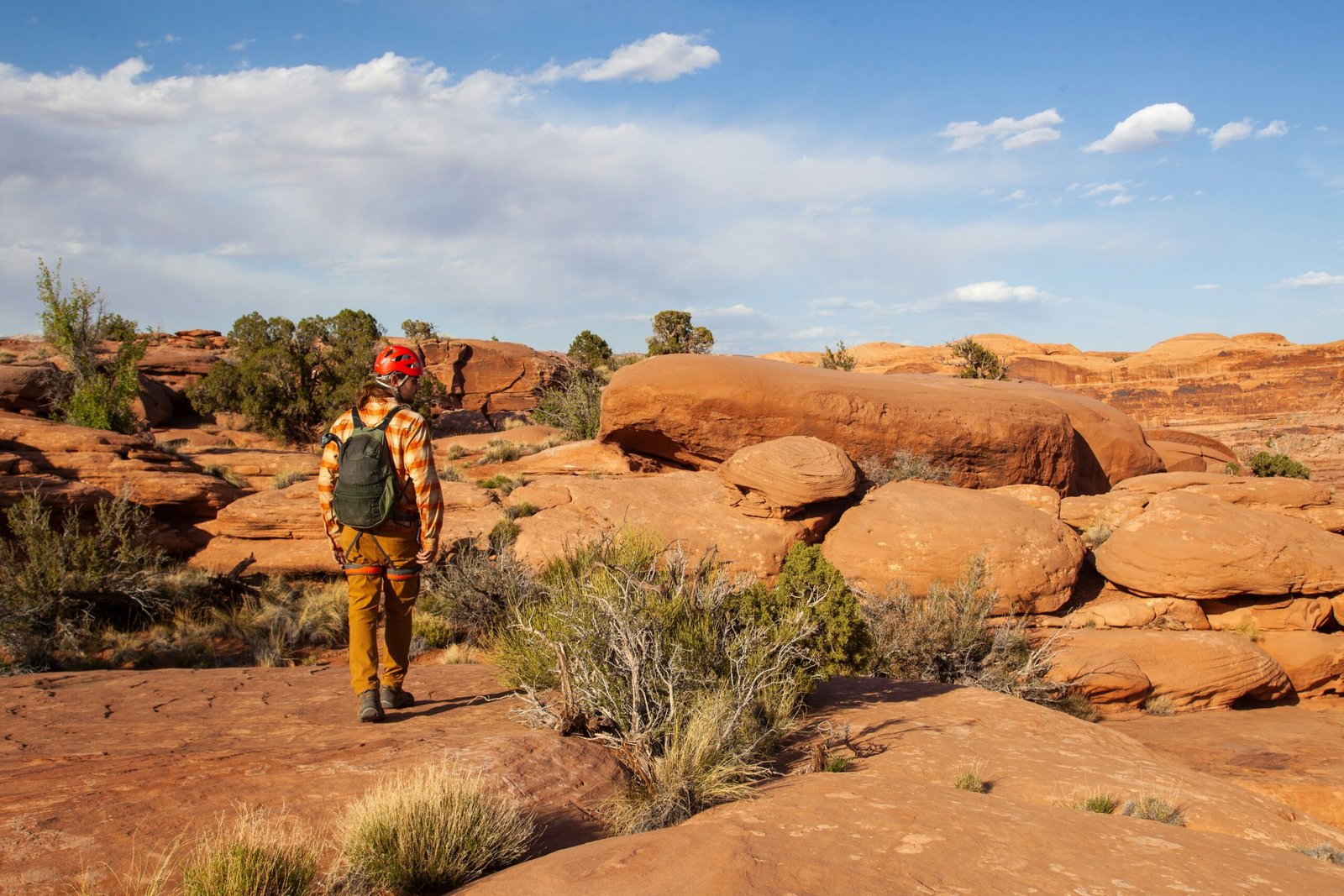 a person wearing a helmet and standing in front of a rock formation